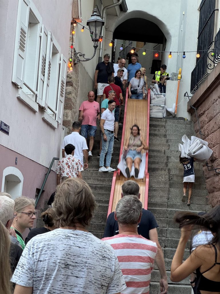 Besucherin rutscht auf der Holzrutsche über die Treppe in der Weinheimer Altstadt